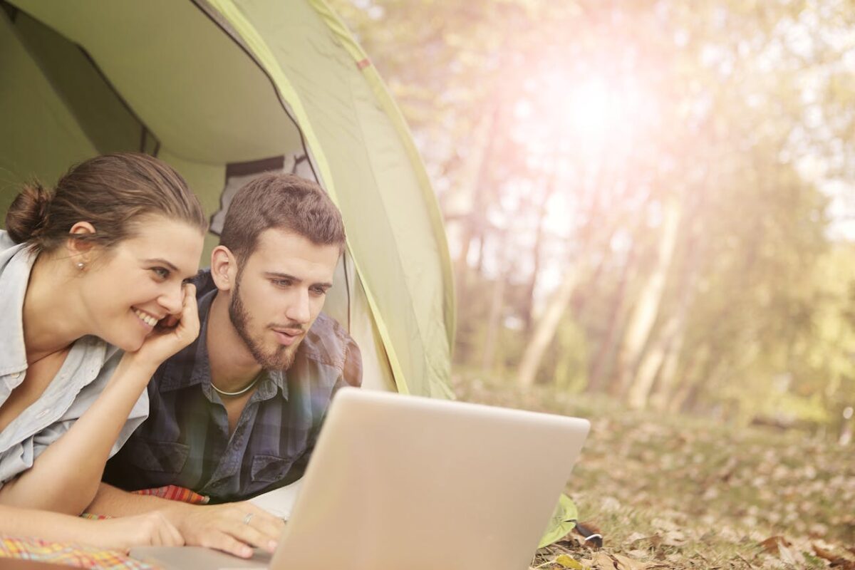 couple-lying-on-tent-using-computer-laptop
