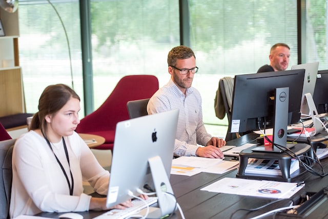 three people are sitting at computers in the office