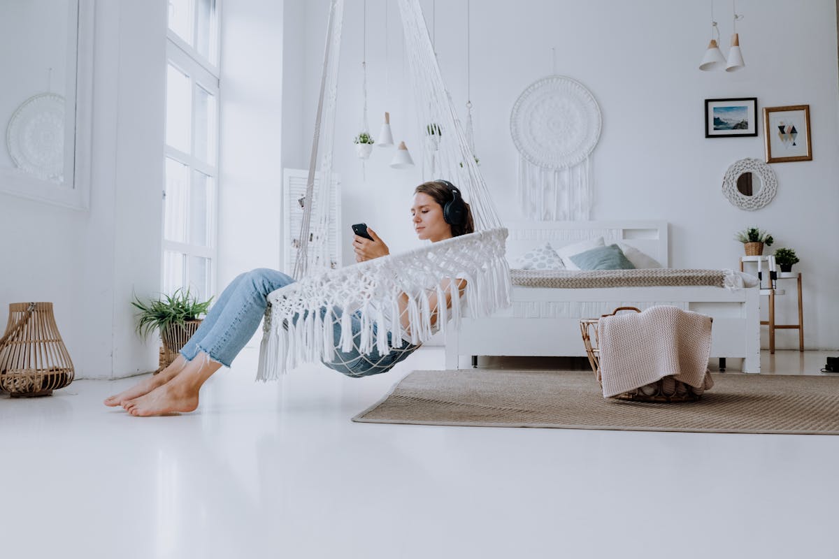 Woman in White and Blue Long Sleeve Shirt and Blue Denim Jeans Lying on White Bed