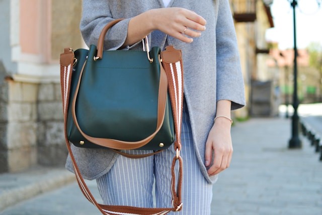 women-standing-while-carrying-green-and-brown-leather