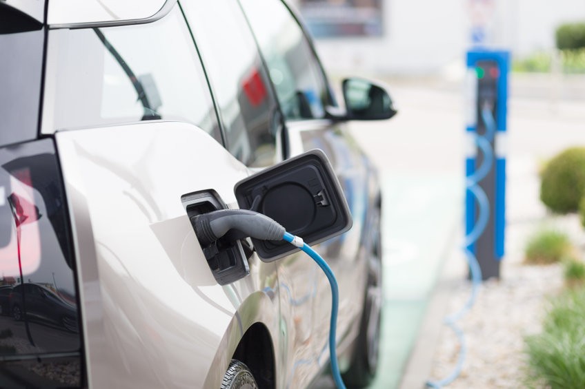 Power supply for electric car charging.  Electric car charging station. Close up of the power supply plugged into an electric car being charged.