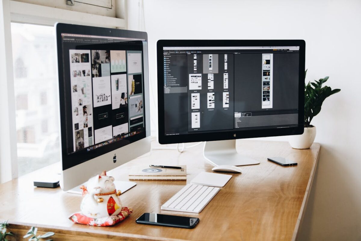 two-imac-s-with-keyboard-and-phones-on-desk