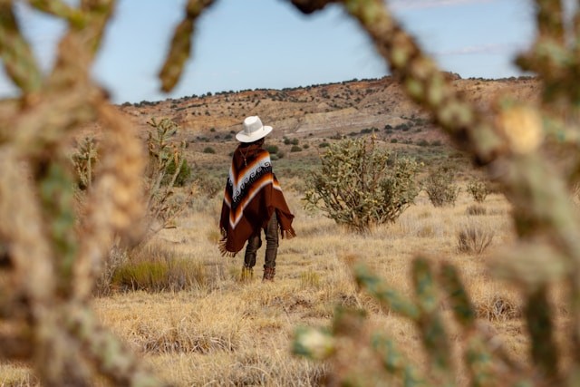 woman-in-red-and-black-long-sleeve-shirt-and-white-hat-standing-on-brown-grass-field